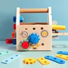 A wooden toy toolbox with various tools and accessories laid out on a light blue surface against a light blue background. Produktbild-Vorschau