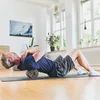 A man is using a foam roller on his back in a bright, airy room. Anteprima dell’immagine prodotto