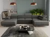 A modern living room with a large grey sectional sofa, a coffee table, and plants.