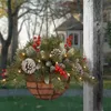 A Christmas hanging basket decoration with pine needles, pinecones, and red berries, adorned with fairy lights, is displayed outdoors next to a wooden post. Anteprima dell’immagine prodotto
