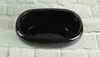A dark oval ceramic planter sits on a white brick wall. Produktbild-Vorschau