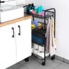 A black metal roll cart with four shelves filled with bathroom supplies and towels, placed next to a white cabinet and sink in a bathroom. Náhled obrázku produktu