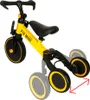 A yellow and black children's tricycle is shown against a white background. The tricycle has three wheels, a seat, handlebars, and pedals. The rear wheels are shown in a wider stance, indicating adjustability. Podgląd zdjęcia produktu