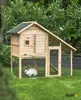 A wooden rabbit hutch with a rabbit inside, set in a grassy garden with trees in the background. Produktbild-Vorschau