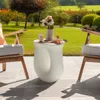 A stylish white side table with a vase of flowers and a drink on it, placed on a patio next to chairs. Náhled obrázku produktu