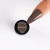 A finger with a nail polish is shown next to a small jar of nail polish. Produktbild-Vorschau