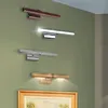 Four picture lights of different finishes mounted on a green wall above a framed painting. Podgląd zdjęcia produktu