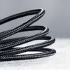 A close-up, coiled black braided cable against a light gray background. Produktbild-Vorschau