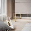 A close-up view of a white high-heeled shoe placed on a wooden floor next to a modern cabinet with golden legs and a beige curtain in the background. Náhľad obrázku produktu