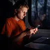 A young man is using his phone on a train at night. Anteprima dell’immagine prodotto