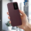 A hand holding a burgundy phone case with a clear view window, showing a phone screen with time and date. Podgląd zdjęcia produktu
