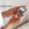 Hands holding an open charging case for wireless earbuds. Produktbild-Vorschau