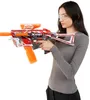 A woman wearing safety glasses is holding a toy gun with orange gel pellets. Voir les images du produit
