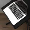 A laptop is placed on a black folding table, which is on a wooden floor. The background is a gray wall. Náhľad obrázku produktu