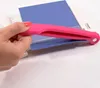 A hand is holding a pink paper cutter over a blue piece of paper. Anteprima dell’immagine prodotto
