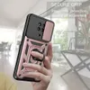 A hand holding a rose gold phone case with a slide camera cover and ring holder, with a blurred indoor background. Produktbild-Vorschau