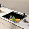 A black kitchen sink filled with various fruits, placed on a white countertop. Produktbild-Vorschau