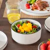 A table setting with a salad bowl, a glass of water with lemon, and a plate of steak. Voir les images du produit