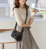 A woman is holding a cup and wearing a black leather shoulder bag. Anteprima dell’immagine prodotto