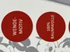 Two red circular stickers with text on a white and gray background with faint Mickey Mouse outlines. Produktbild-Vorschau