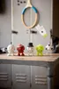 Five decorative figures resembling sports balls are lined up on a wooden table in front of a locker. Produktbild-Vorschau