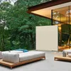 A modern outdoor living space with a sectional sofa, a room divider, and a low table, surrounded by lush greenery. Produktbild-Vorschau