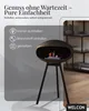 A modern black bioethanol fireplace with a unique oval design and three legs, shown indoors with a blurred background of a shelf and decor. Podgląd zdjęcia produktu