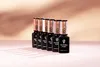 A row of identical nail polish bottles on a pink surface with a blurred peach background. Náhled obrázku produktu