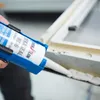 A person is using a caulking gun to apply sealant to a window frame. Produktbild-Vorschau