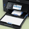 Close-up of the front of a black Epson printer with paper loaded in the input trays. Náhled obrázku produktu