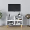 A white TV stand with wooden legs is shown in a room, with a TV mounted on the wall above it. Podgląd zdjęcia produktu