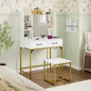 A white and gold vanity set with a mirror and stool is shown in a bedroom setting. Náhľad obrázku produktu
