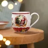 A Christmas-themed mug sits on a wooden table, with blurred lights in the background. Voir les images du produit