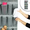 A close-up view of a grey fabric hanging organizer with multiple pockets. A person's hands are shown placing white slippers into one of the pockets. Another pocket contains a pink cloth, and the bottom pockets show two hairbrushes. A small inset image show Produktbild-Vorschau