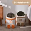 Two astronaut-shaped trash cans are placed on a carpet next to a bed and a nightstand. Produktbild-Vorschau