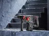 A cordless hammer drill is placed on a concrete ledge in front of a set of dark stairs. Produktbild-Vorschau