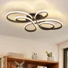 A modern ceiling light fixture with a swirling design, mounted on a white ceiling. Voir les images du produit
