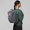 A woman wearing a green sweatshirt and black pants is seen from the side, wearing a gray backpack. Produktbild-Vorschau
