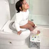 A young child is sitting on a toilet with a potty training seat and a step stool. Náhled obrázku produktu