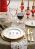 A festive Christmas table setting with nutcracker-themed plates, glasses of water and wine, and a red pitcher. Produktbild-Vorschau