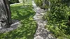 A garden path made of gravel curves through a lawn, bordered by trees and shrubs. Anteprima dell’immagine prodotto