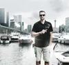 A man stands on a dock holding a set of hex keys, with boats and city buildings in the background. Produktbild-Vorschau