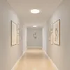 A well-lit hallway with artwork on the walls and ceiling lights. Náhľad obrázku produktu
