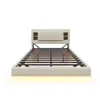 A beige upholstered bed frame with a slatted base and a headboard with built-in storage compartments and LED lighting. Produktbild-Vorschau