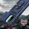 A blue phone case with a ring holder and camera cover is shown on a rocky, uneven surface, suggesting durability and protection. Produktbild-Vorschau