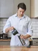 A man pouring coffee into a travel mug in a kitchen. Anteprima dell’immagine prodotto