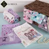 A collection of girls' underwear with various patterns and cartoon prints, arranged on a light blue surface next to a woven basket and a pearl necklace. Produktbild-Vorschau