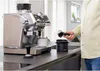 A person is using an espresso machine and knock box in a kitchen setting. Náhled obrázku produktu