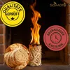 A burning fire starter log is shown in a fireplace, with a close-up of the material and marketing labels. Produktbild-Vorschau