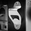 A close-up shot of a metal bottle opener attached to a black surface. Produktbild-Vorschau